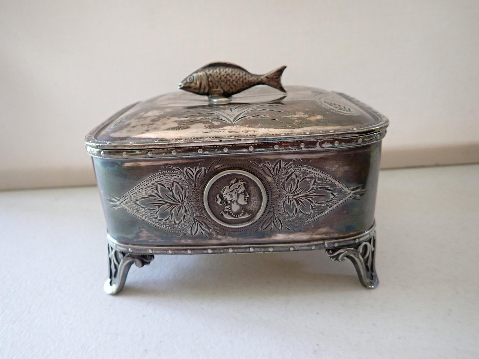 Meriden Silverplate Sardine Box: Ornate footed box with embossed cameo design, sardine finial, and engraved design. Approximately 5" x 4" x 4" high.