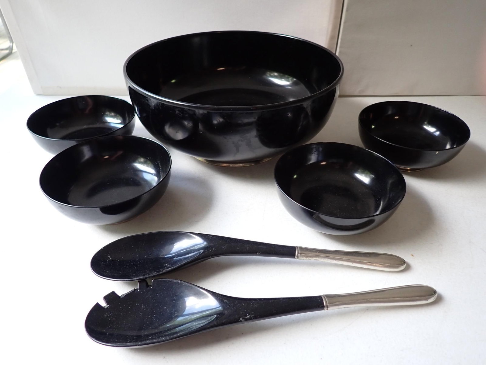 Mid-Century Towle Sterling and Black Melamine Salad Set: Footed Bowl with sterling rim. Sterling Handled Salad Utensils. The tooth on one is broken. Bowls show some wear from use but overall good condition.