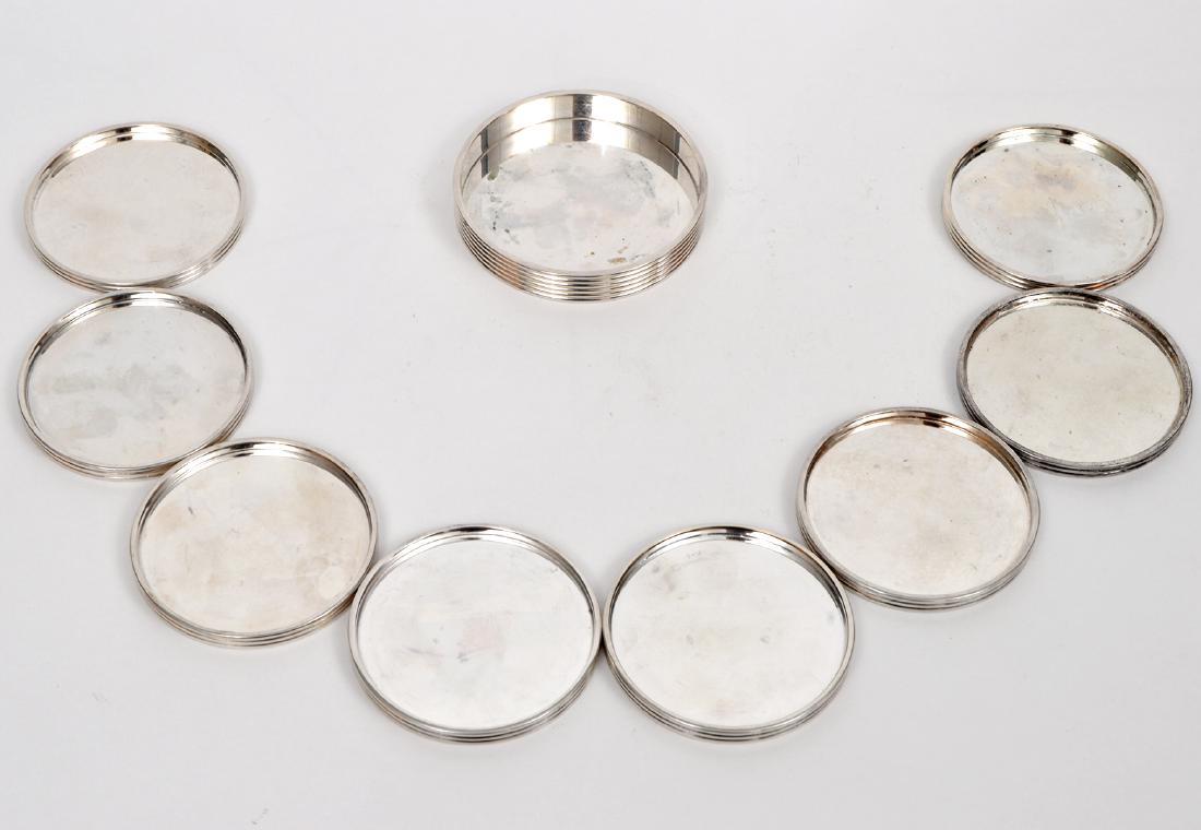 9 pcs Christofle Silverplate Modernist Coaster Set: 9 piece Christofle silver-plate modernist wine bottle coaster & 8 silver-plate glass coasters set. Wine coaster: 4"D x .75"H, Glass coasters: 3.5"D x .25"H. Marked on bottom: Christofle, K + T. Condit