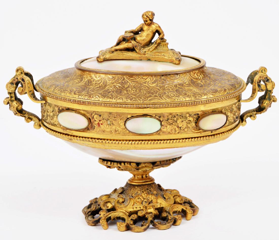 Mother of Pearl Guilt Footed Oval Box: Vintage guilt box featuring an ornate pedestal foot, mother of pearl body and accents, and a woman finial. The lid is hinged and the latch releases by pushing one of the mother or pearl medallions. 4.