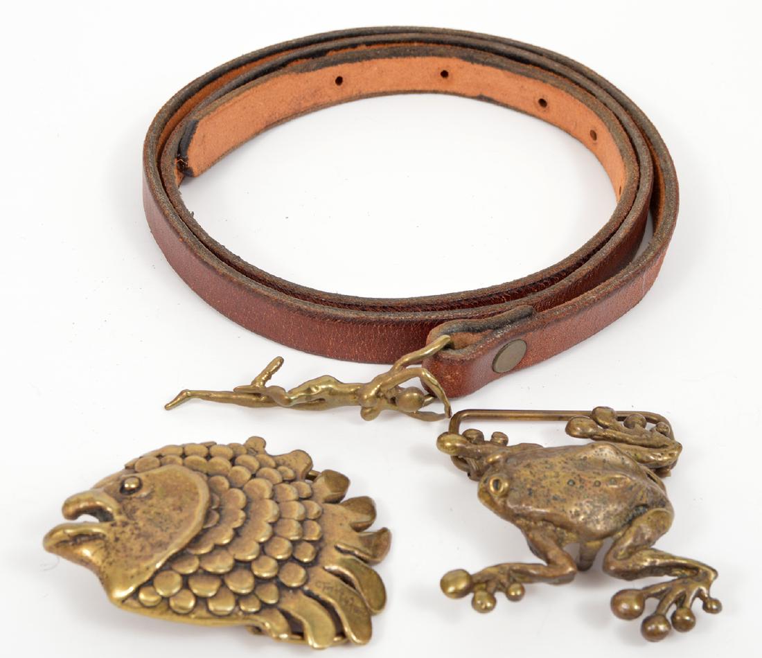 3 Carl Tasha Brass Belt Buckles Signed: 3 Carl Tasha brass belt buckles. A frog, a fish and a nude on a leather belt. ranging in size from 3.5 - 2.75"L. Signed & dated. Condition Report: Very good - leather belt shows wear. Please examine a