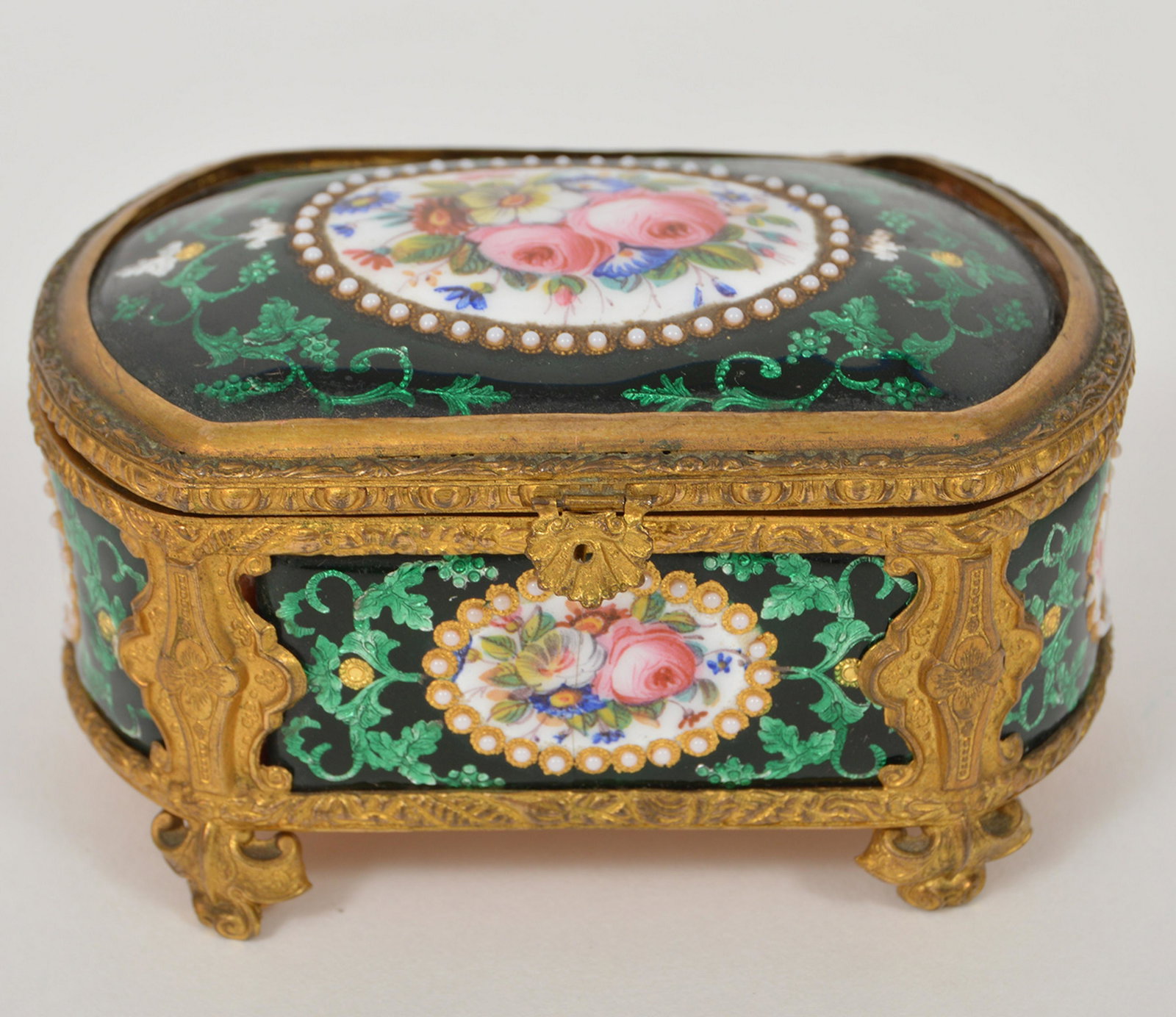 Antique Gilded Porcelain Trinket Box: Antique gilded hand painted and foiled flower and leaf designed trinket box. Lined in pink satin. 1.5"Hx3.5"Lx2.5"W. Condition report: Good- porcelain is loose on the top, on ding in gilded metal. Ple