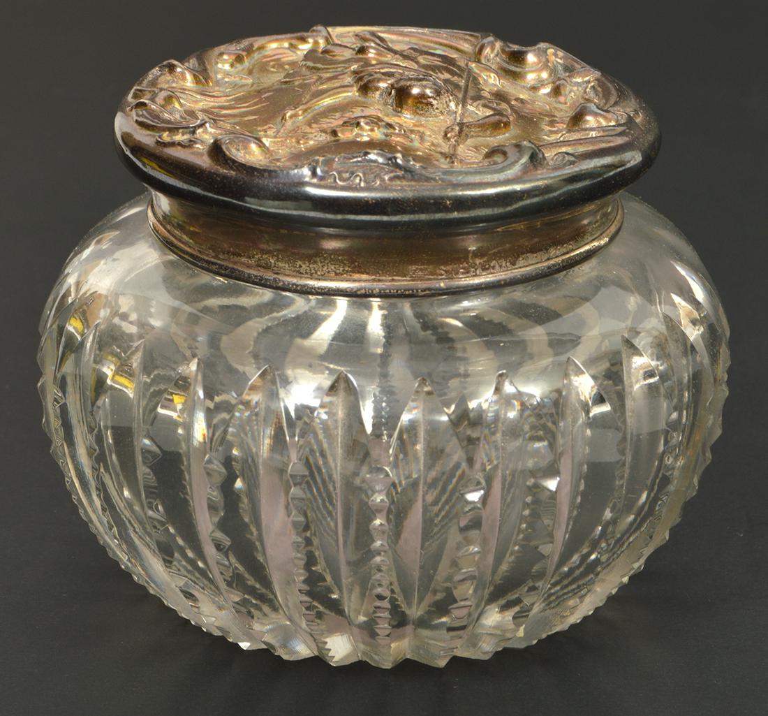 Art Nouveau Foster & Bailey Dresser Jar: Art Nouveau exceptional Foster & Bailey dresser jar featuring a highly detailed repousse sterling silver lid of a couple on a swing over a cut glass jar. 2.5"H, 3.75" diameter. 22.1 grams silver. Cond