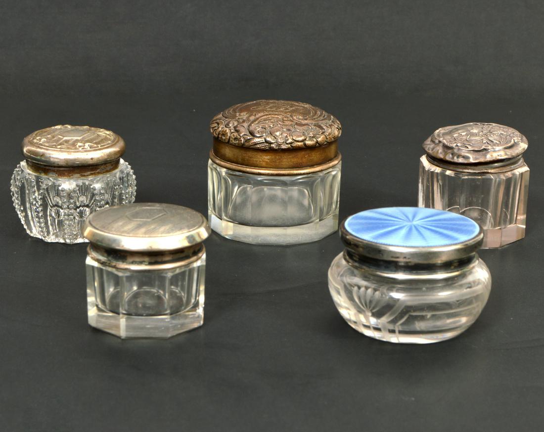 5 Sterling Silver & Glass Small Dresser Jars: Lot of 5 dresser jars with sterling silver lids on cut and etched glass jars: 3 jars have repousse lids, one has an engraved lid and one boasts a blue guilloche lid. Jars range from 1.25" to 1.5"H. To