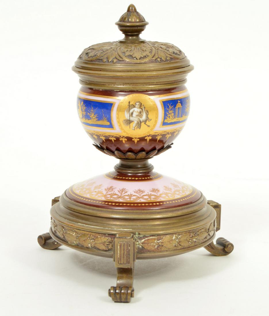 French Antique Bronze and Porcelain Inkwell: French antique bronze and porcelain inkwell on 3 scrolled feet. Bronze lid and finial are decorated with leaves and body & base have colorfully painted porcelain frieze bands. Measures 6.25"H x 4.75"W