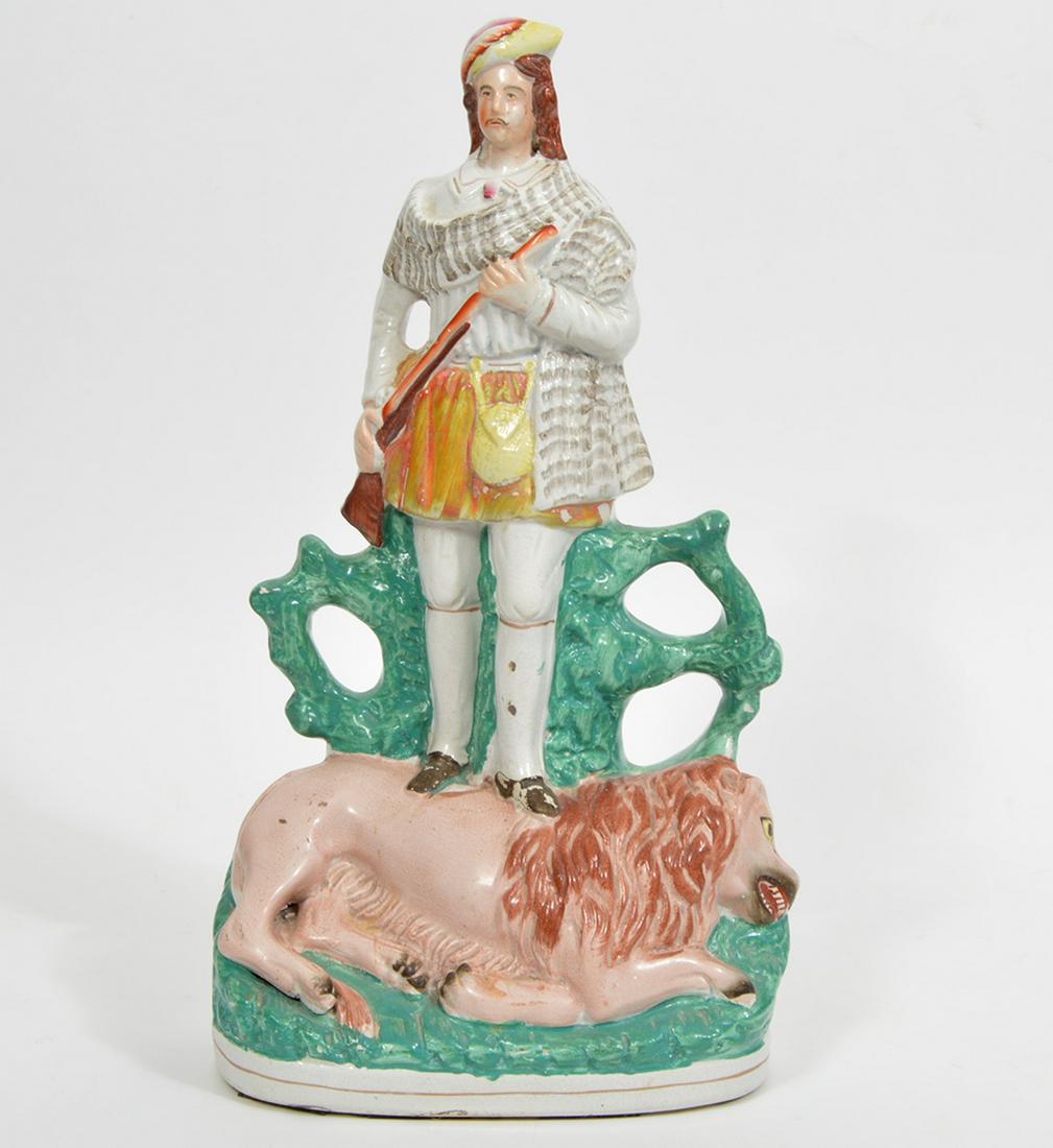 Staffordshire Lion Hunter Statue: Staffordshire figure of man wearing traditional Scottish clothing holding a rifle and standing on a lion. Measures 16.25"H x 4.25"W x 8"L. Condition report: good condition, some paint loss, see photos
