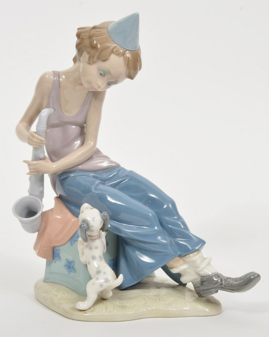 Lladro Clown with Saxophone and Dalmatian Puppy: Lladro porcelain figure of a young clown playing the saxophone and a young Dalmatian puppy at his side. Retired in 1985. Measures 10.5"H x 9"L x 5"W. Condition report: good condition, no issues, see p