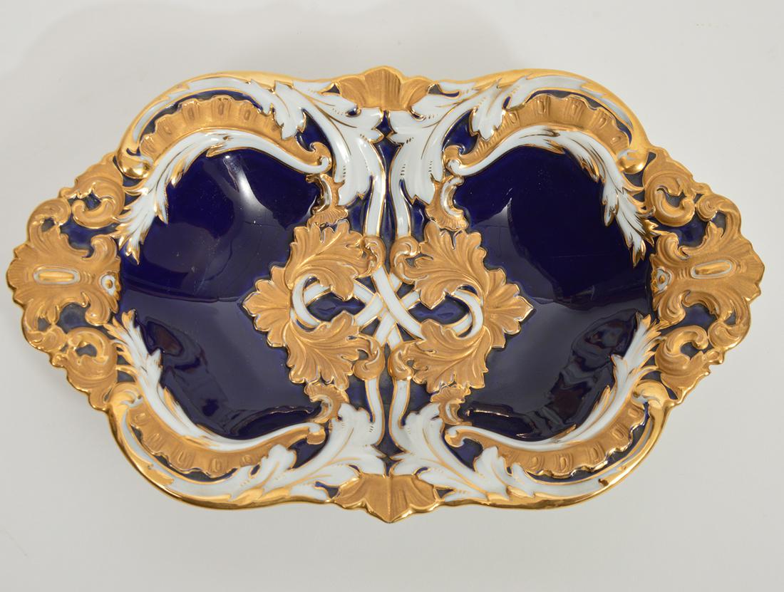 Meissen Porcelain Cobalt Blue & Gold Enamel Bowl: Meissen Cobalt blue & gold enamel bowl in a Rocco-style foliate motif. Designed by Ernst August Leuteritz. Measures approximately 12" L x 7.75" W x 2.5"H. Genuine hallmarks on underside. Condition rep