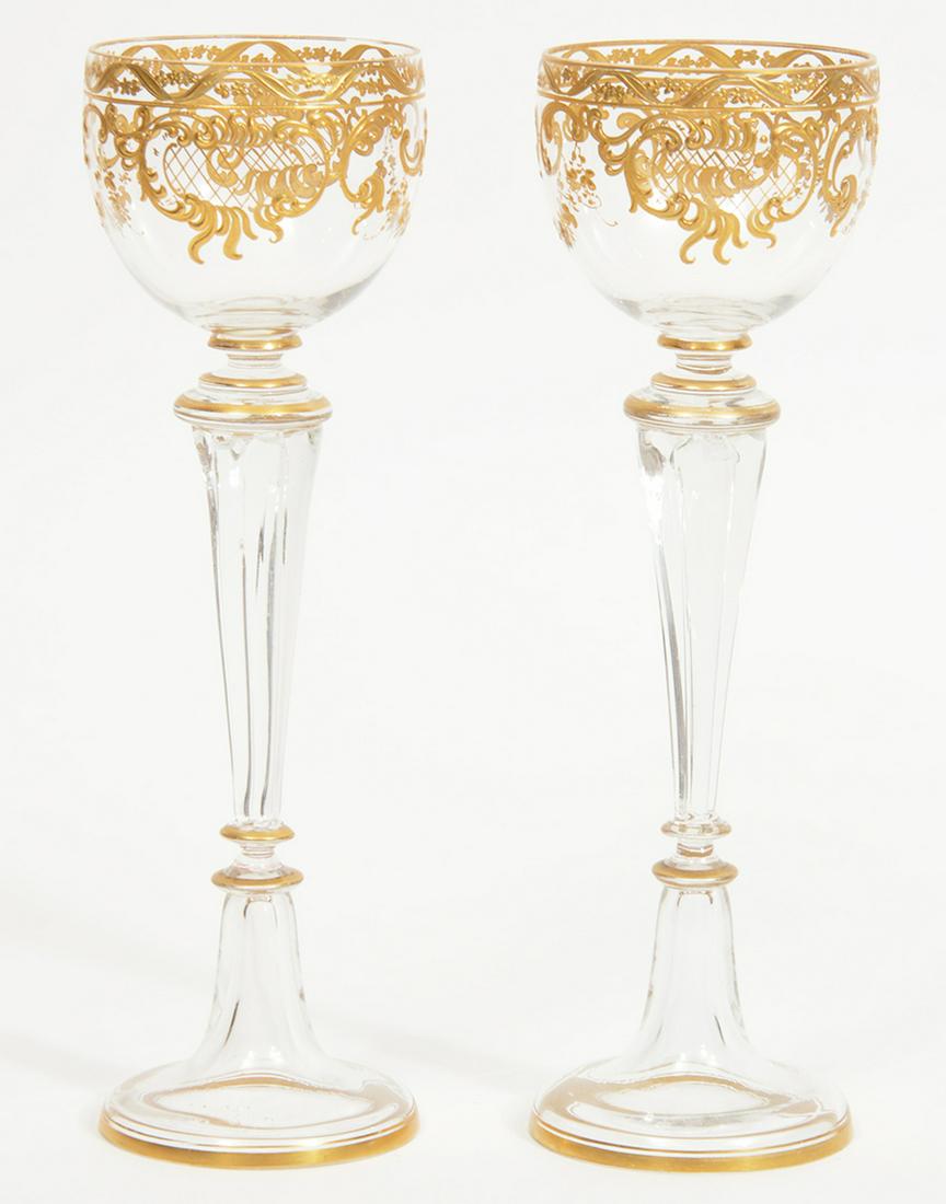 Pair of Bohemian Gilt Wine Goblets Attrib. Moser: Two Bohemian hand-painted gilt over clear wine glasses attributed to Moser. 8.75"H, 2.75"W at mouth. Condition report: Good, very minor missing gilt, very minor imperfection in glass made during blowi