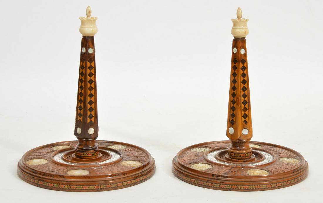 Pr. Judaica Torah Scoll Holders: Pair Wood Judaica Torah Scoll Holders (2 of 4)with Inlaid wood, and bone. on craved bases with silver ring and Hebrew writing. 9.5” H x 7.5” D. Condition report: Good, 1 chip on the inside ring on