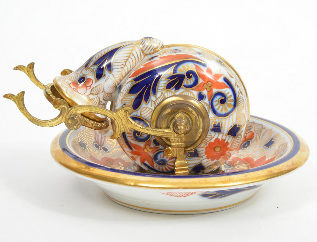 Fischer & Mieg Porcelain Imari-Style Snail Inkwell: Late 19th century, Fischer & Mieg of Pirkenhammer porcelain hand-painted Imari-style snail-form revolving inkwell, with brass pen holder and underplate. Green hallmark on underside. Measures 7"W x 3.5