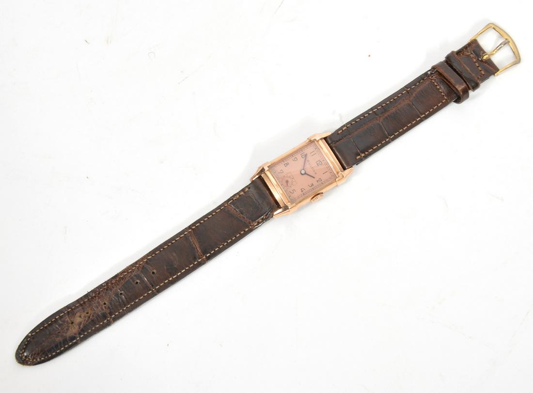 1940s Bulova Excellency 'TT' 14K Gold Filled Watch: 1940s Bulova Excellency 'TT' 14K gold filled man's wristwatch, coral colored face, thick raised crystal, 21 jewels, non-original brown leather band. Case width approximatly 21mm. Weight - 27.9g. Condi