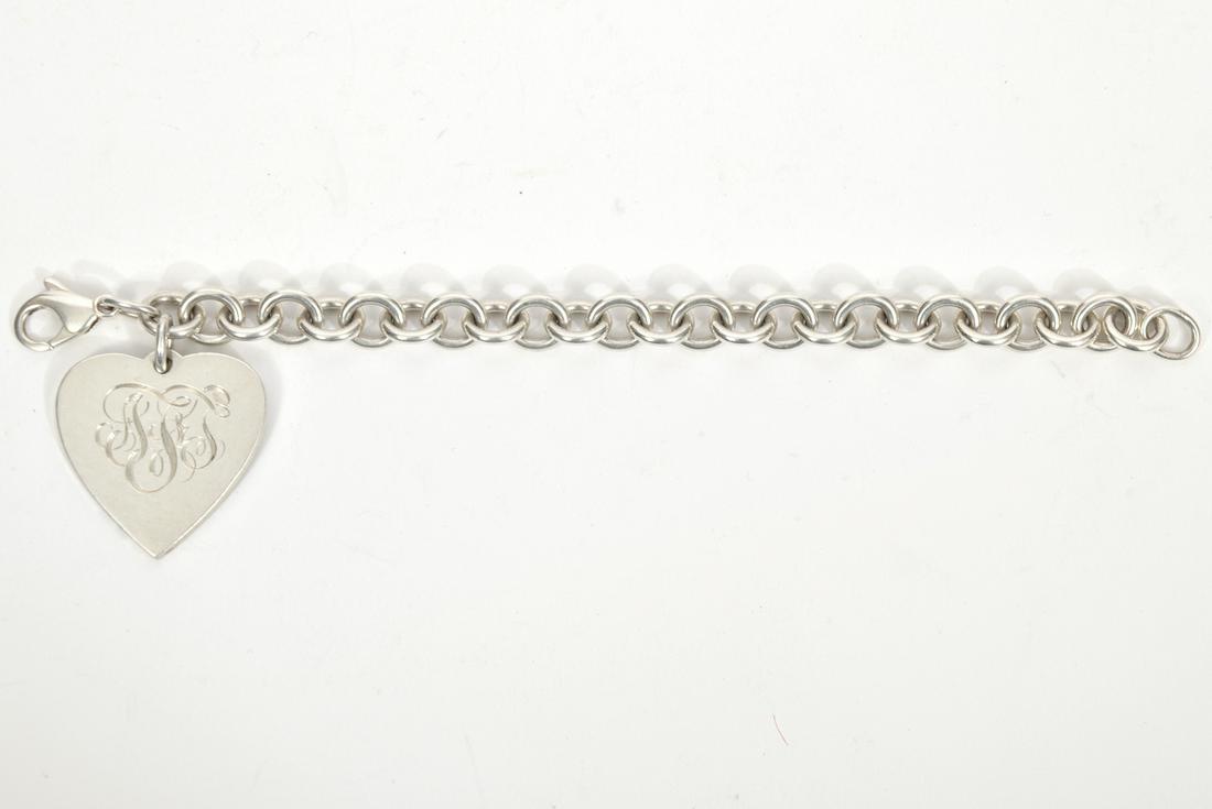 Tiffany & Co Sterling Silver Bracelet: Tiffany & Co. sterling silver bracelet with large heart charm. Heart charm is marked Tiffany and monogrammed on one side. Measures 7 1/4" long, weighs 44.7 grams. Condition report: good. Provenance fr