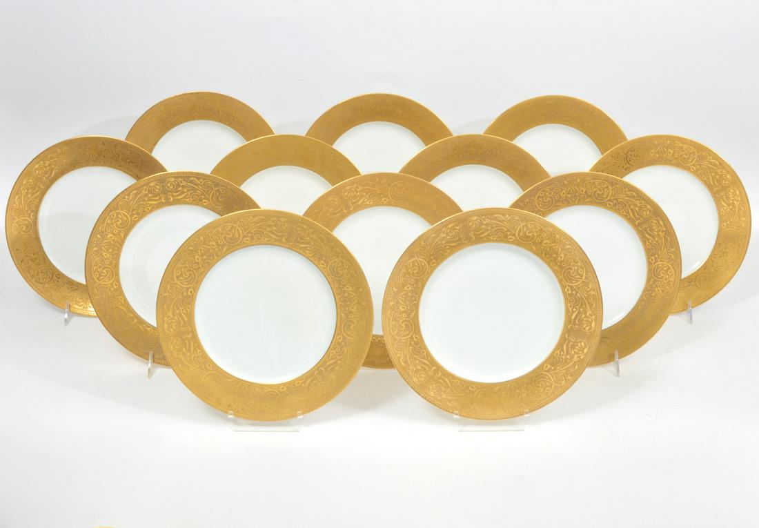 12 Hutschenreuther Bavarian Gilt Dinner Plates: Set of 12 Hutschenreuther Bavarian porcelain dinner plates with scrolling gilt patterns on border. Each plate measures approximately 10.5" in diameter. Underside hallmarked. Condition report: Good con