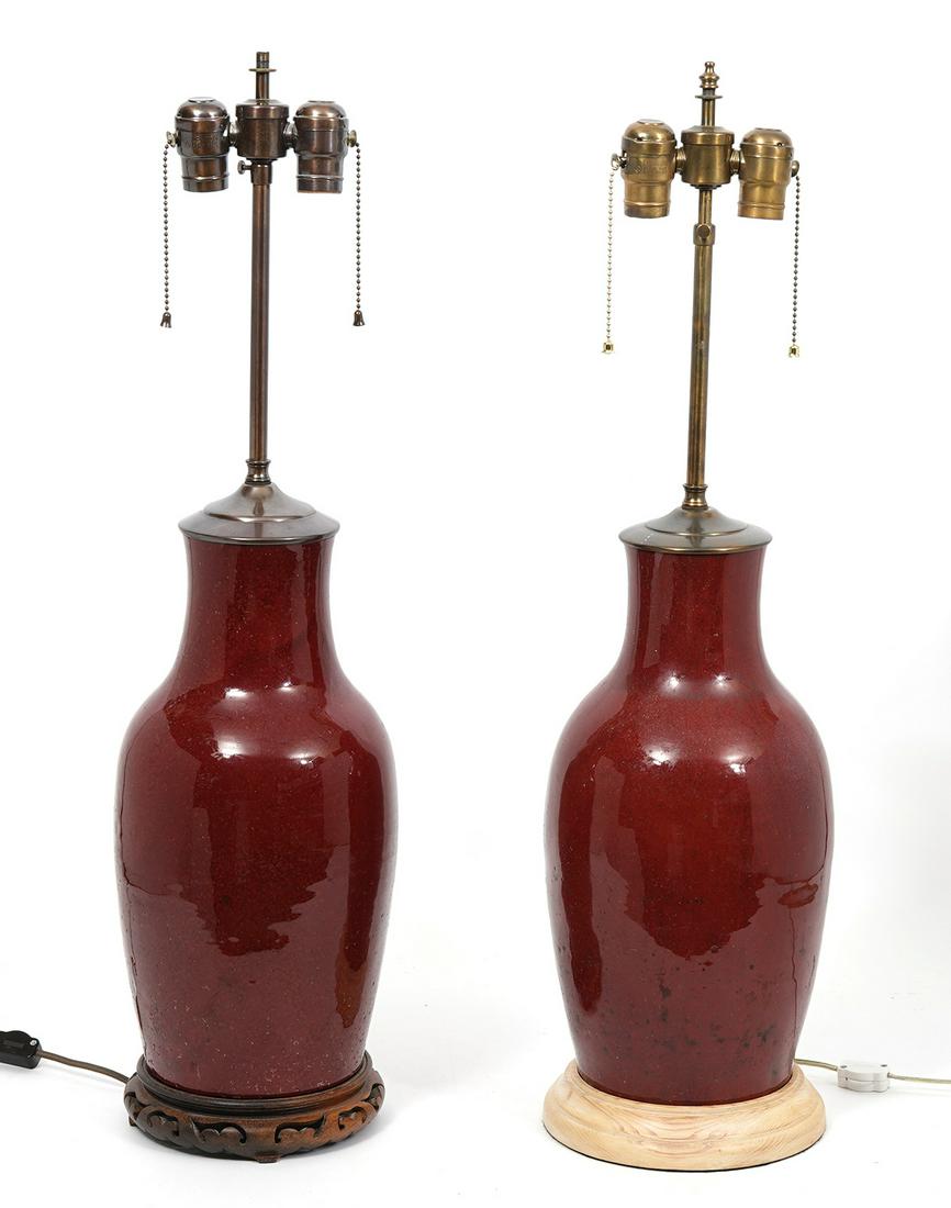 Pr. Chinese Sang De Boeuf Oxblood Lamps: Pair of Chinese sang de boeuf oxblood vases converted to lamps. Each having a different wood base. Vase measures 16"H x 7.5"W. Total height about 29". Condition report: Good condition, minor wear norm