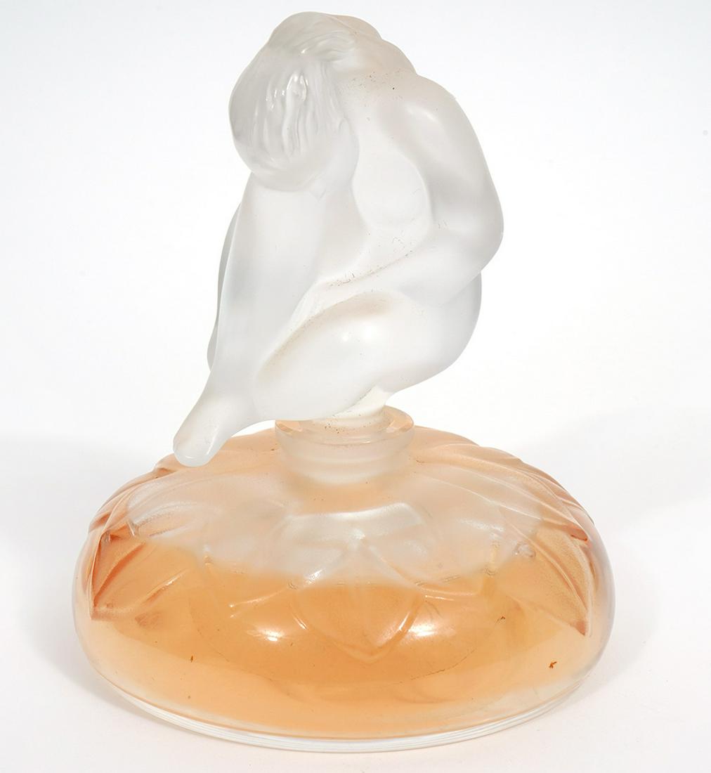 Lalique Frosted & Molded Crystal Perfume Bottle: Lalique pressed and partially frosted & molded crystal perfume bottle decorated with flower petals and nude female top. Etched on underside 'Lalique France' with original label. Measures 4.25"H x 3.25