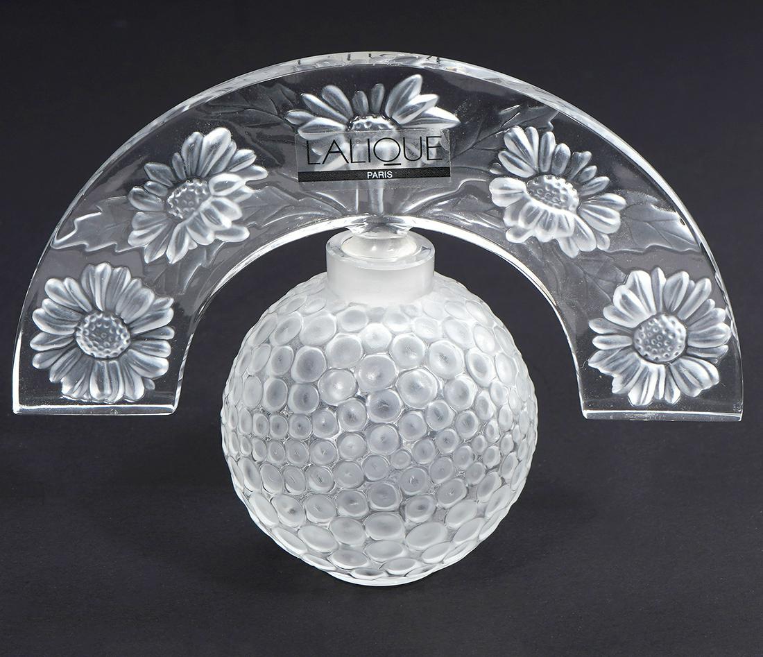 Lalique 'Folie' Crystal Perfume Bottle: Lalique 'Folie' crystal perfume bottle has spherical body accented with frosted circles and a fan shaped stopper etched with daisies. Marked 'Lalique France' on base. Measures 3.75"H x 5"L x 2"W. Cond