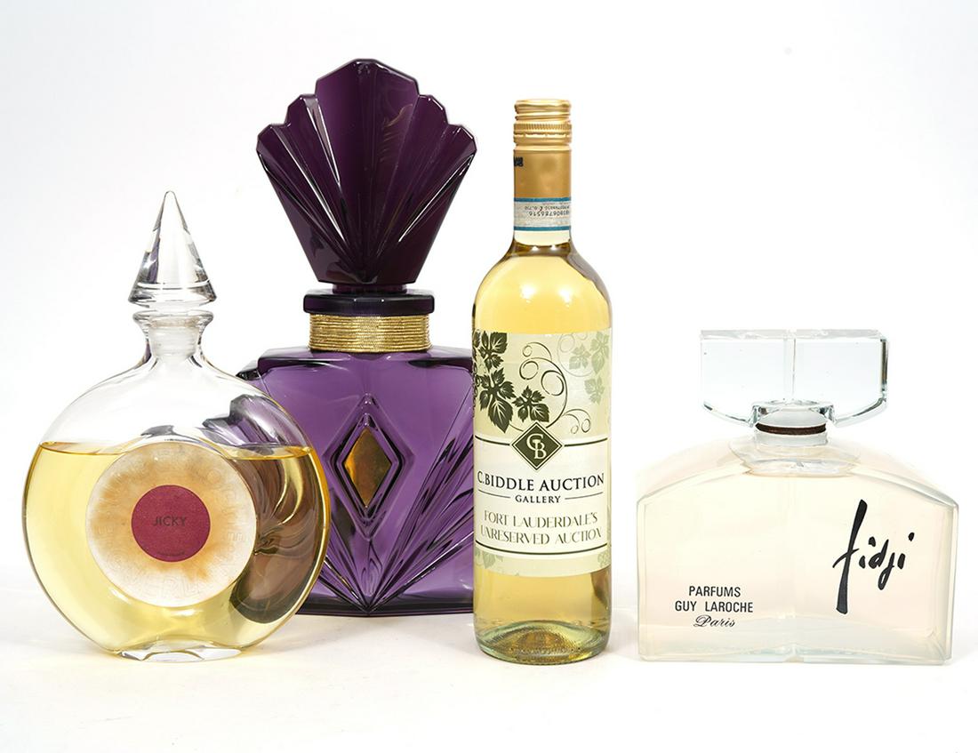Three Designer Glass Factice Bottles: Guerlain Jicky Eau de Cologne, partially full, measures 6.25"L x 1.75"W x 9.5"H; Guy Laroche Fidji, full, measures, 6.5"L x 3"W x 6.75"H; Elizabeth Taylor Passion, measures 8.5"L x 3"W x 12.5"H. Condi