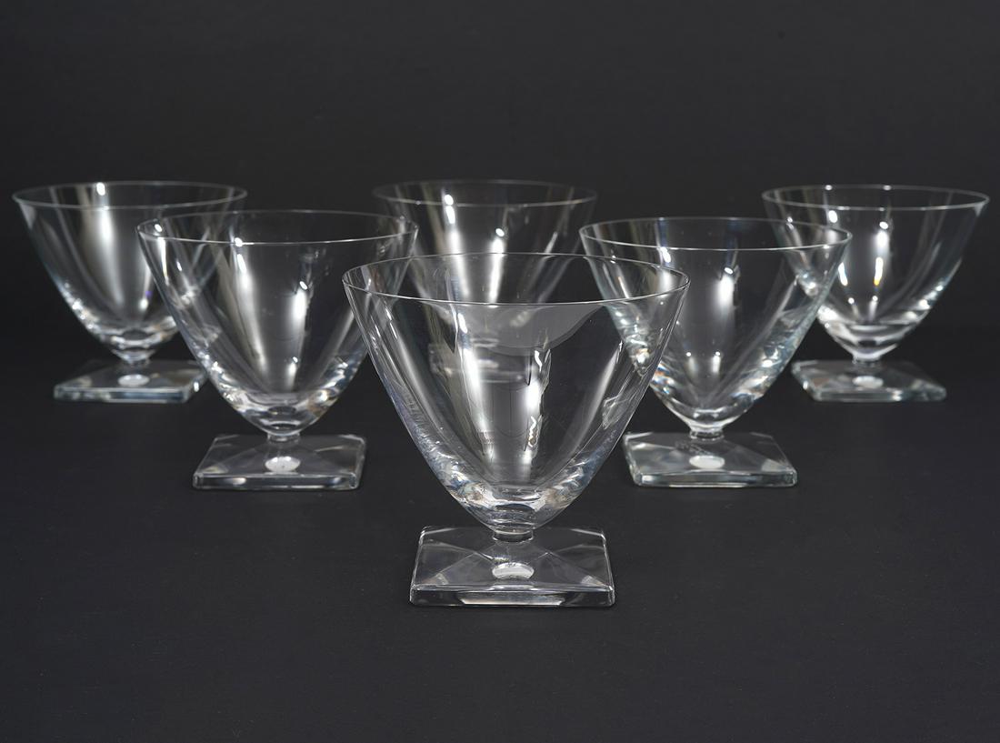 6 Lalique Contemporary Cocktail Glasses: 6 Lalique crystal cocktail glasses, featuring contemporary modern design. Tapered form and beveled square foot. Hallmarked underside. Measures 3.5"W x 3.75"H. Condition report: Good condition, no issu