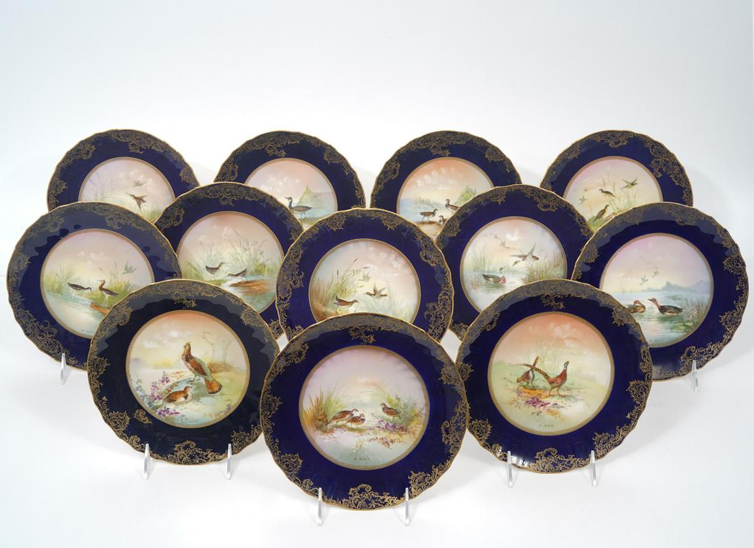 12 Theodore Haviland Game Plates Signed: 12 Theodore Haviland game plates signed 'L. Martin'. Cobalt blue accented with gilt scrolled designs and scalloped rims with hand painted circular game scenes. Measures 8.5"W. Condition report: good c