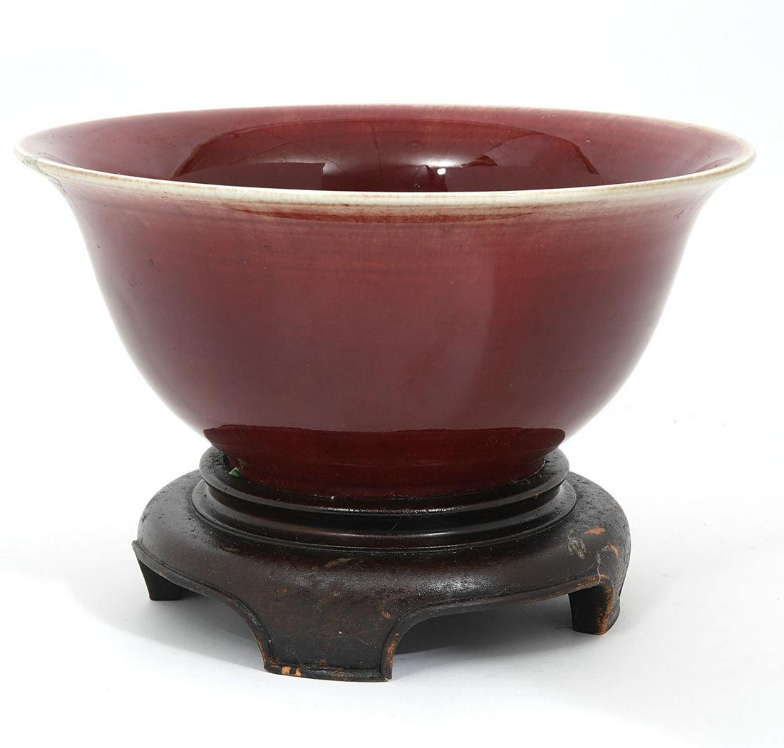 Chinese Sang de Boeuf Glazed Oxblood Bowl: Chinese large Sang de Boeuf glazed oxblood bowl on stand. Measures 7"H (with stand) x 10.5"W x 5.25" H (Bowl). Condition report: good condition, one repaired chip around top edge, see photos. Contact 