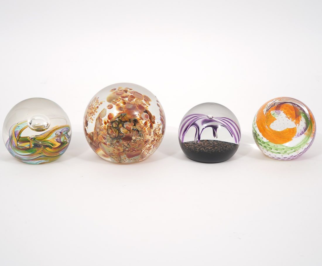 Four Signed Art Glass Paperweights: Group of four art glass paperweights includes: Serkirk Scottish studio glass 'Mardi Gras' 1998 #18/50. Swirling color with center suspended bubble (3"H x 3.25"W). "Mardi Gras" 2002, #19/100, bubbles w