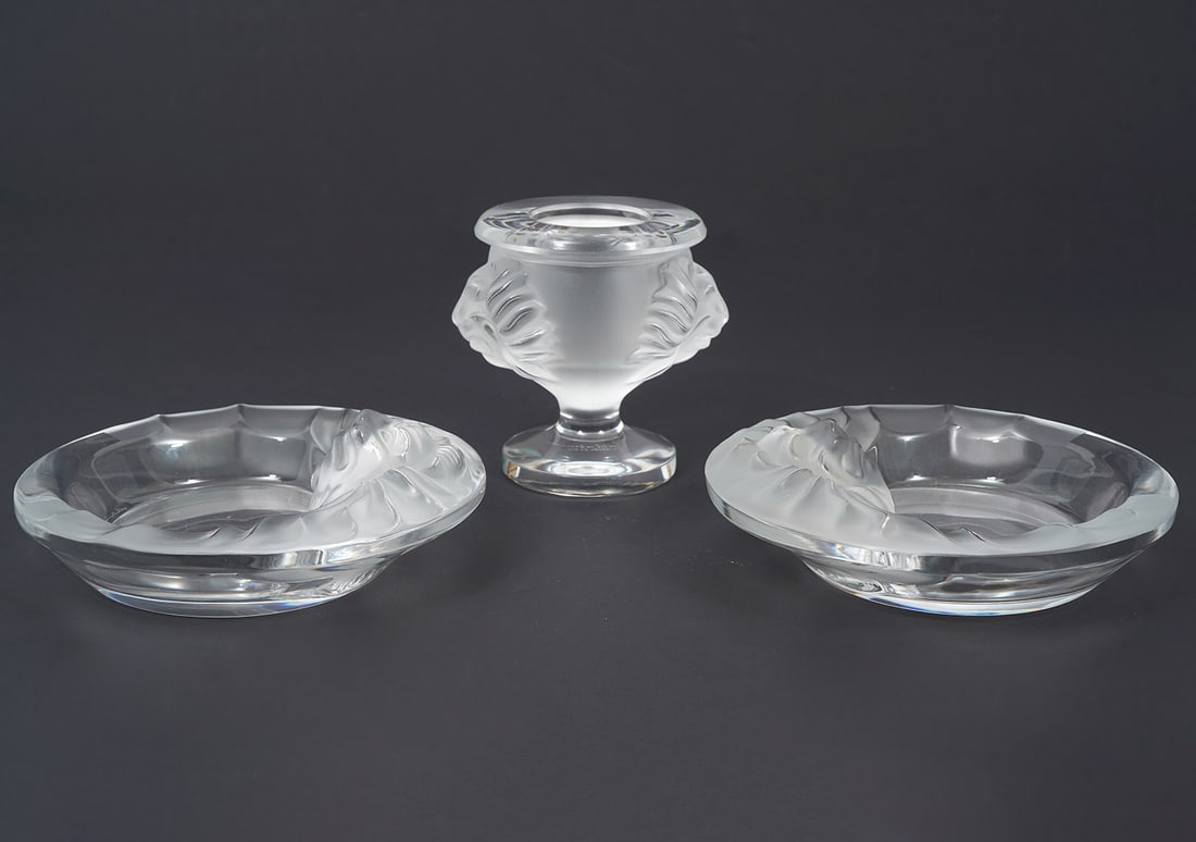 Lalique 'Tete de Lion' Lighter Holder & 2 Ashtrays: Lalique crystal 'Tete de Lion' lighter holder with double lion heads (3.75"H x 4"W) and 2 lion head ashtrays (6"W x 1.75"H) all in satin and clear crystal, etched Lalique France on each. Condition rep