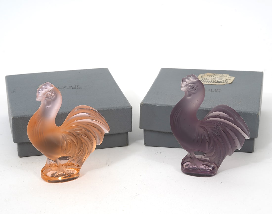 2 Art Glass Lalique Cockerel Roosters: 2 Lalique art glass Cockerel Roosters in lavender and pink. Both are signed 'Lalique France' and include the original boxes. Measures 3"H x 2.5"W. Condition report: good condition, please see all phot