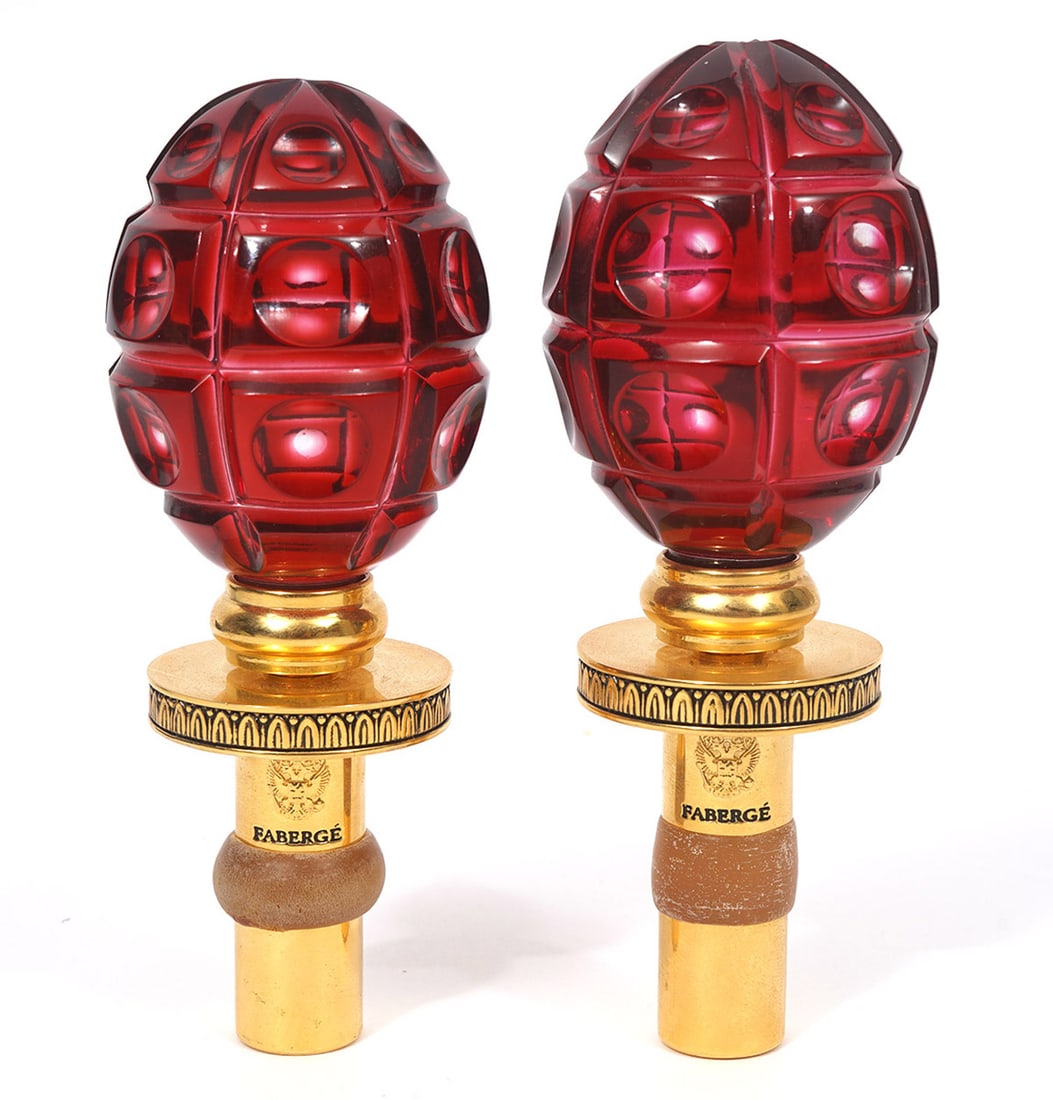 Two Faberge Germany Red Crystal Gilt Stoppers: Two Faberge Germany wine stoppers, composed of red egg-shaped crystal and gilt metal. Measures 5" long. Condition report: Good condition, some wear from use, please examine all photos closely. Contact