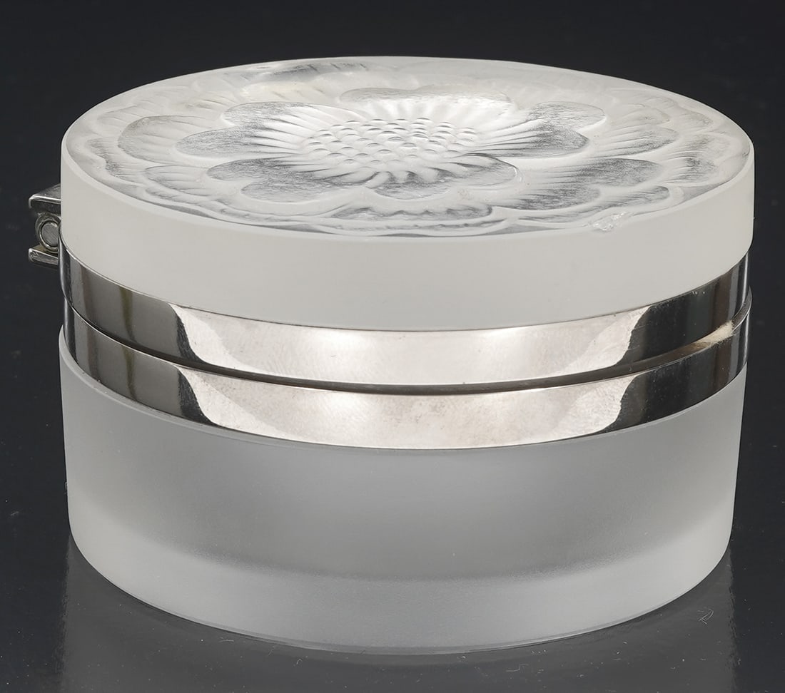 Lalique Frosted Crystal Dresser Box: Lalique frosted crystal dresser box with gold mounts and hinged lid showcasing a carved flower in relief on the top. Signed on bottom 'Lalique France". Measures 1.75"H x 3"W. Condition report: tiny ch