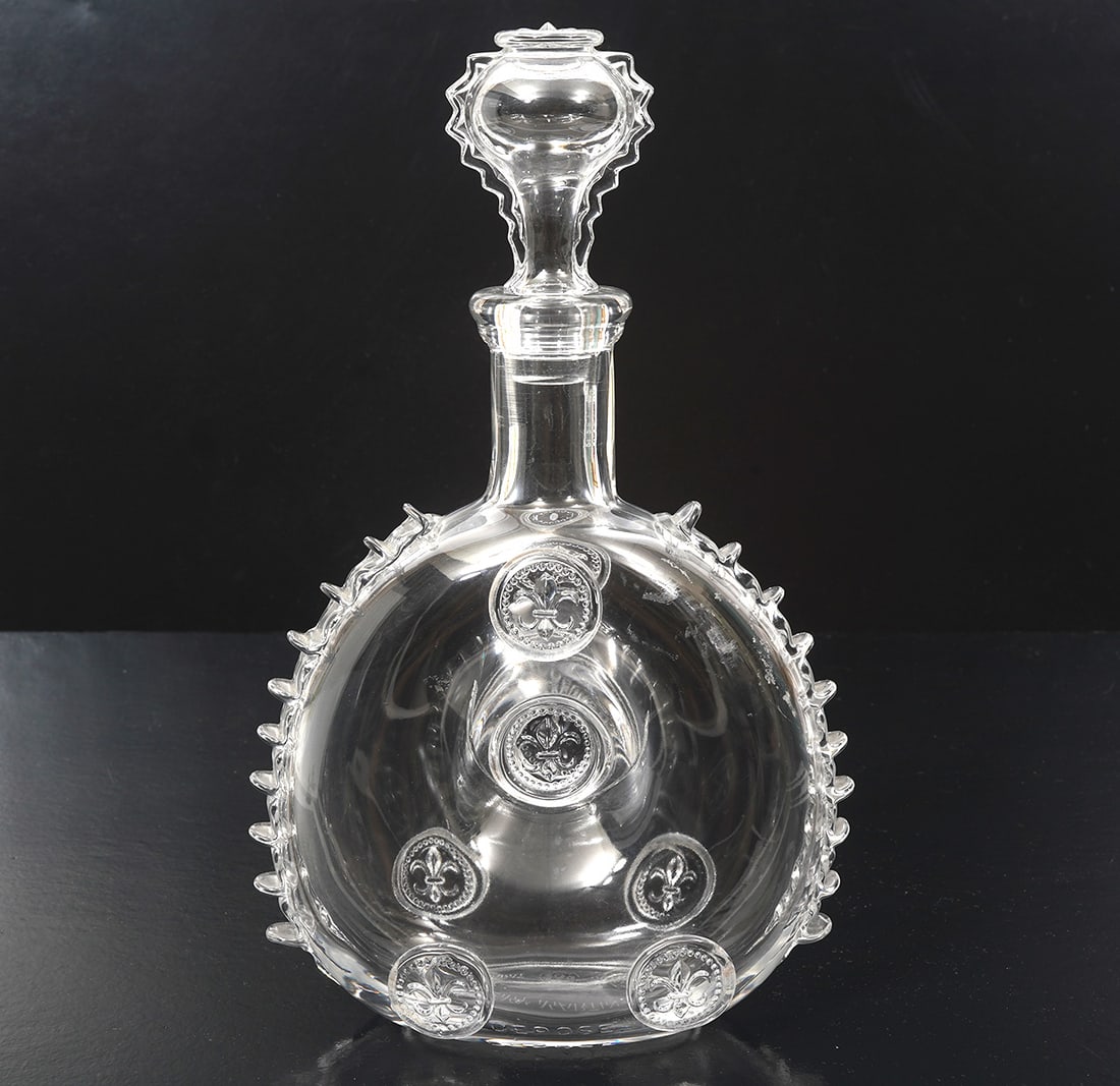 Remy Martin Baccarat Crystal Cognac Decanter: Remy Martin Cognac decanter by Baccarat Crystal features pinched center, ruffled sides and fleur-de-lis seal-style stopper. Measures 11.5"H x 6.5"W. Acid-etched marks underside. Condition report: Good