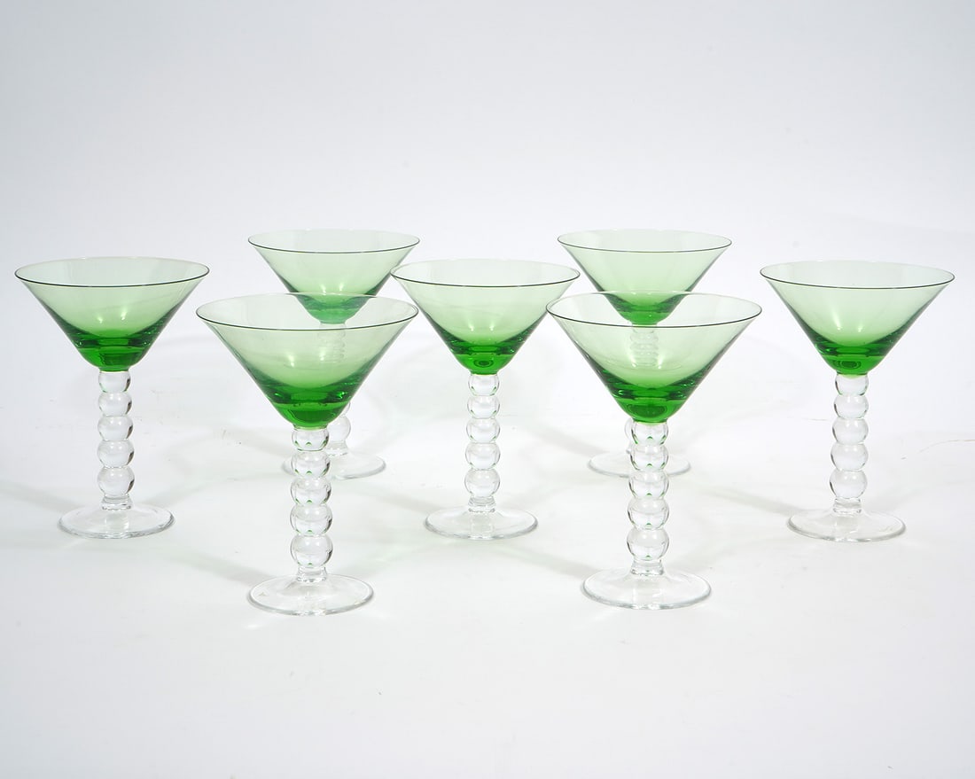 7 Modernist Green and Clear Martini Glasses: 7 Modernist green and clear martini glasses features stacked ball stem and are unsigned. Measures 6.25"H x 4.5"W. Condition report: Good condition, please examine all photos closely. Contact C. Biddle