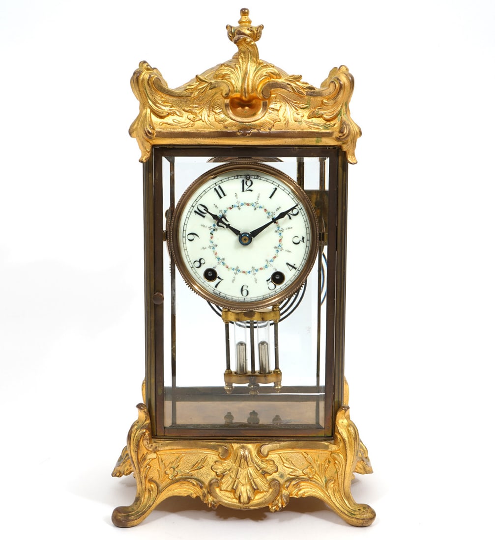 Gilt Bronze Beveled Glass Mantel Clock: Gilt bronze, beveled glass mantel clock . Features sculptural scrolling top and base, white dial with floral accents and includes winding key. Measures 8"L x 6.5"W x 15"H. Condition report: Good condi