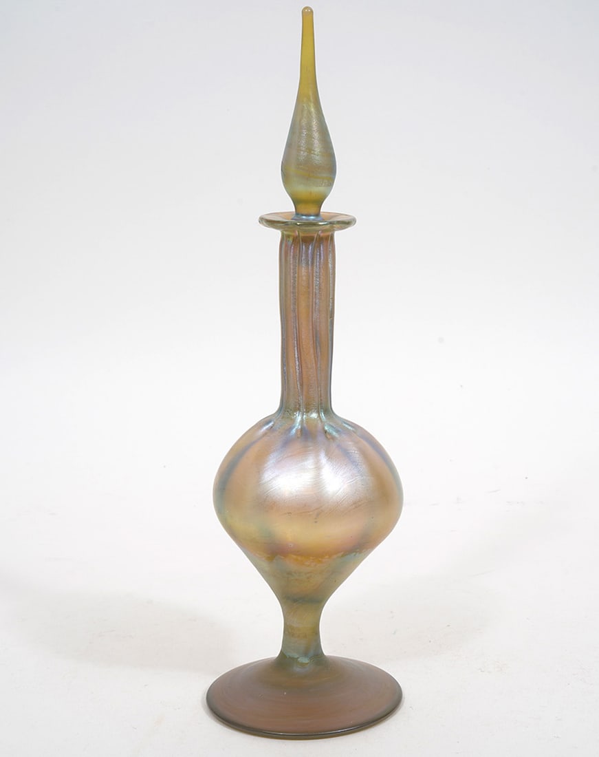 Phoenix Studios Iridescent Art Glass Bottle: Phoenix Studios iridescent art glass bottle has long neck and round body with pedestal base and cone shaped stopper, signed on underside. Measures 12"H (total) x 8.5"H (Bottle) x 3.25"W. Condition rep