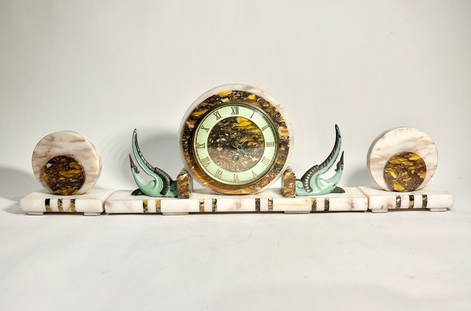 Deco-Style Marble Mantle Clock And Garnitures: Deco-Style marble mantle clock with matching round garnitures, battery powered. Clock measures 19"L x 9.5"H. Garnitures are 6"H x 6"L. Condition report: Good condition, please examine all photos close