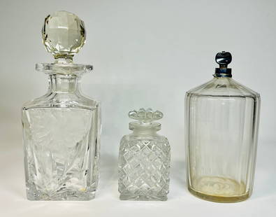 Three Crystal Perfume Vanity Bottles: Diamond cross-hatch pattern square bottle (3.25"H x 1.75"W), Etched floral themed bottle with faceted stopper (7"H x 2.5"W). Cylindrical bottle with silvered cap (5.5"H x 2.75"W). Condition report: Co