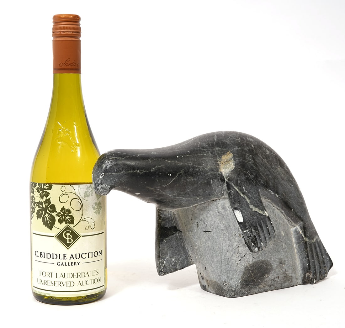 Canadian Inuit Eskimo Carved Sea Lion Figure: Canadian Inuit/Eskimo hand-carved figure is a natural stone sculpture of sea lion resting on rock with original label underside. Measures 11.75"L x 4.5"W x 7"H. Condition report: Some minor chips, ple