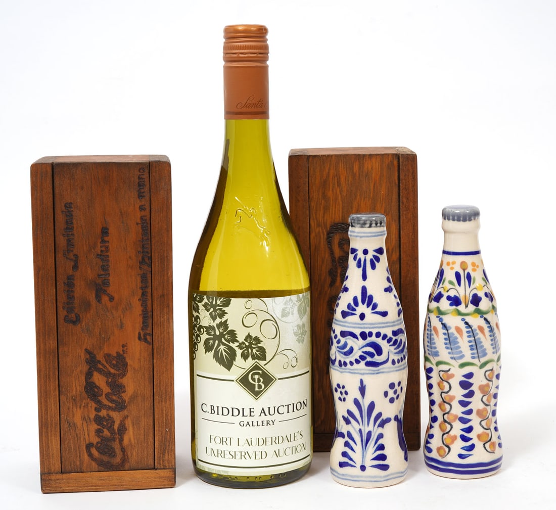 Two Mexican Ceramic Coke Bottles Wood Cased: Two hand-made Mexican (Taladura) ceramic coke bottles in wood cases. Each bottle measures 7"H. Boxes are 8"L x 3.25"W x 3.25"H. One has a piece of matching wood that can be inserted in the back to rai