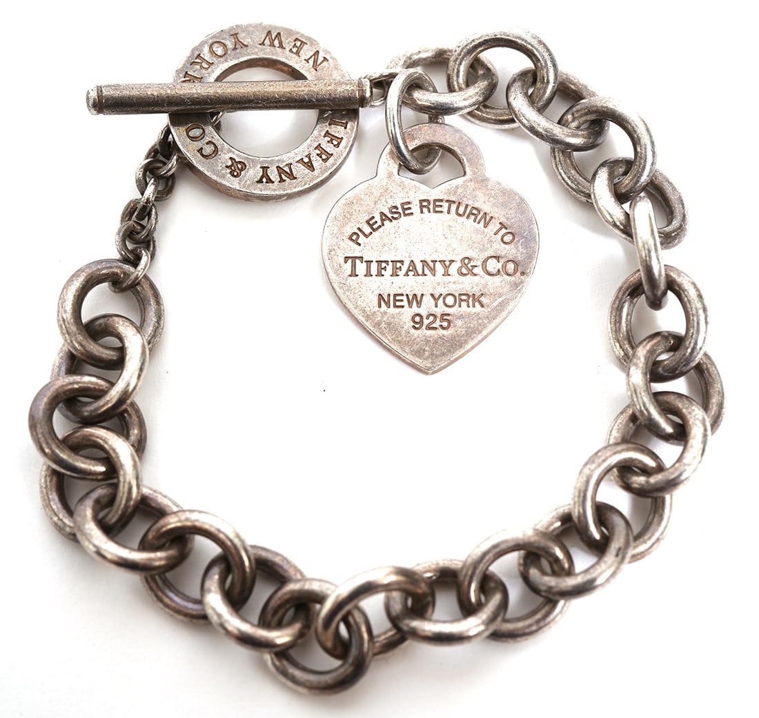Return To Tiffany' Sterling Cable Link Bracelet: Tiffany & Co. classic cable link sterling bracelet with engraved heart charm 'Tiffany & Co. New York 925'. It has a toggle closure and total length is 6.75"L , weighs 36 grams. Condition report: good