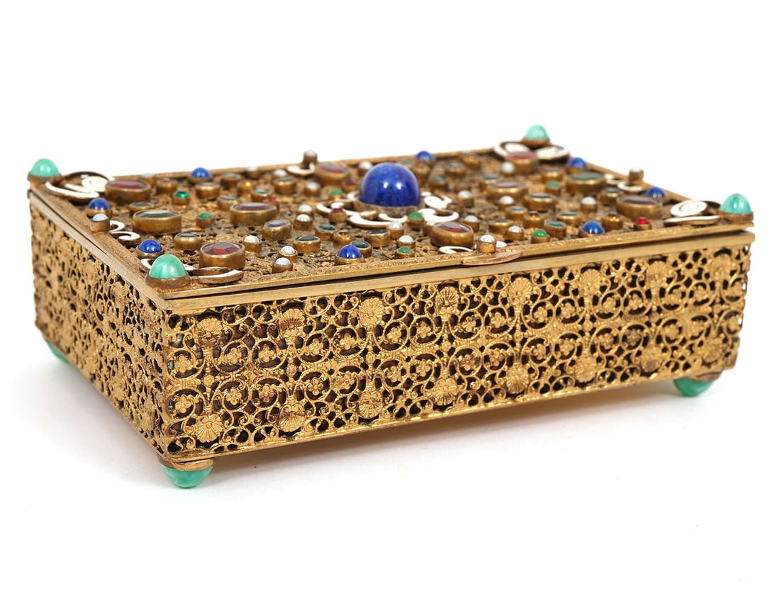 Antique Austrian Jeweled Trinket Box: Antique Austrian trinket box featuring intricate brass filigree work adorned with colored enamel and glass gems on the lid and on the 4 feet on the bottom. Inside has wood lining. Marked 'Made in Aust