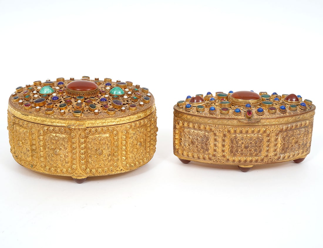 Two Austrian Bronze Oval Jewelry Caskets: Two Austrian bronze oval jewelry caskets with ormolu panel designs on sides and gem stones decorating the tops and bottoms. Both have interiors lined with burgundy velvet. Measurements: 4.75"L x 2"W x