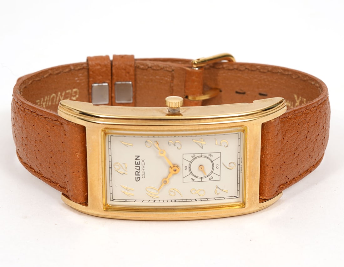 Gruen Curvex Gold-Plated Wristwatch: Gruen Curvex gold-plated curved wristwatch (22mm) with tan pigskin band. Includes original box. Engraved personalization on back. Condition report: Good condition, please examine all photos closely. C