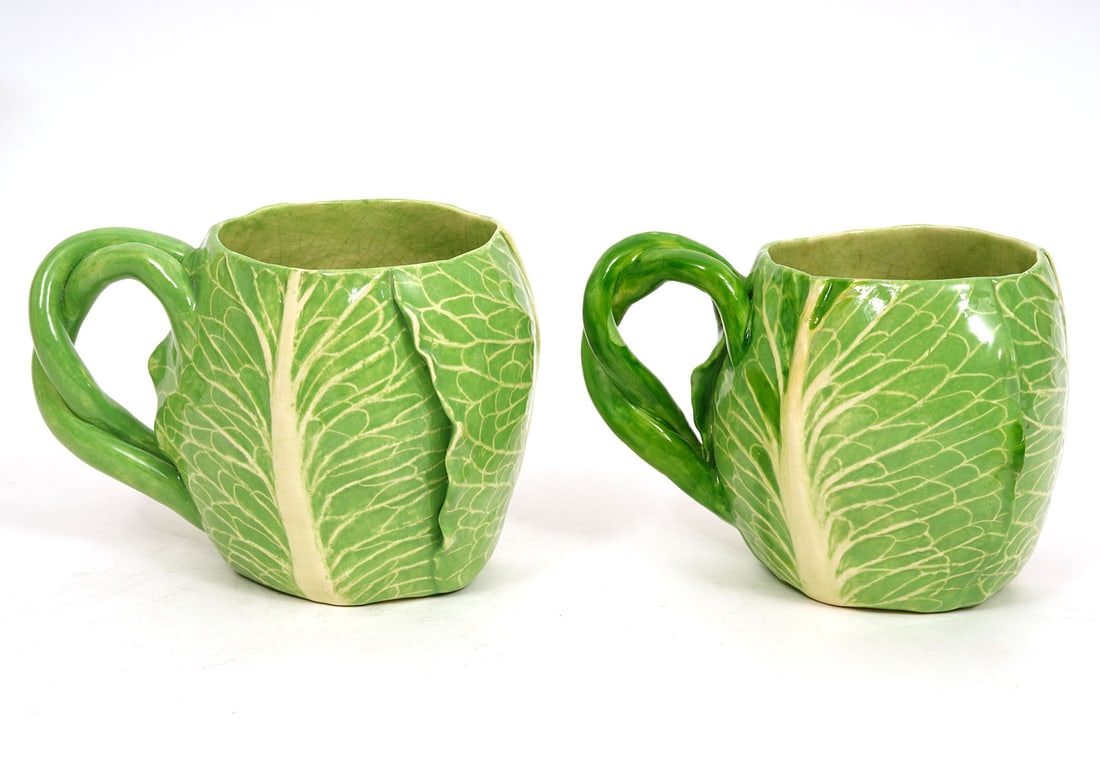 Pair of Dodie Thayer Lettuce Leaf Coffee Mugs: Pair of Dodie Thayer lettuce leaf earthenware coffee mugs signed underside. Each measures 4"H x 5.5"W. Condition report: Good condition, minor repair to handle, please examine all photos closely. Cont