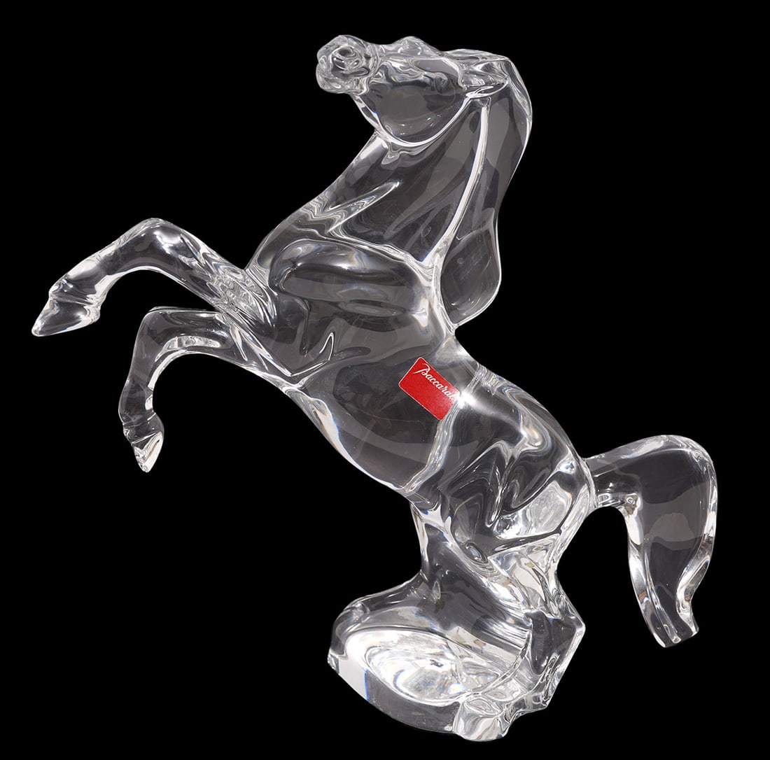 Baccarat Clear Crystal Rearing Horse Figurine: Baccarat clear crystal rearing horse figurine with front legs raised has red Baccarat label on side and is marked on underside. Measures 8"L x 7 7/8"H x 3.25"W. Condition report: good condition, no is