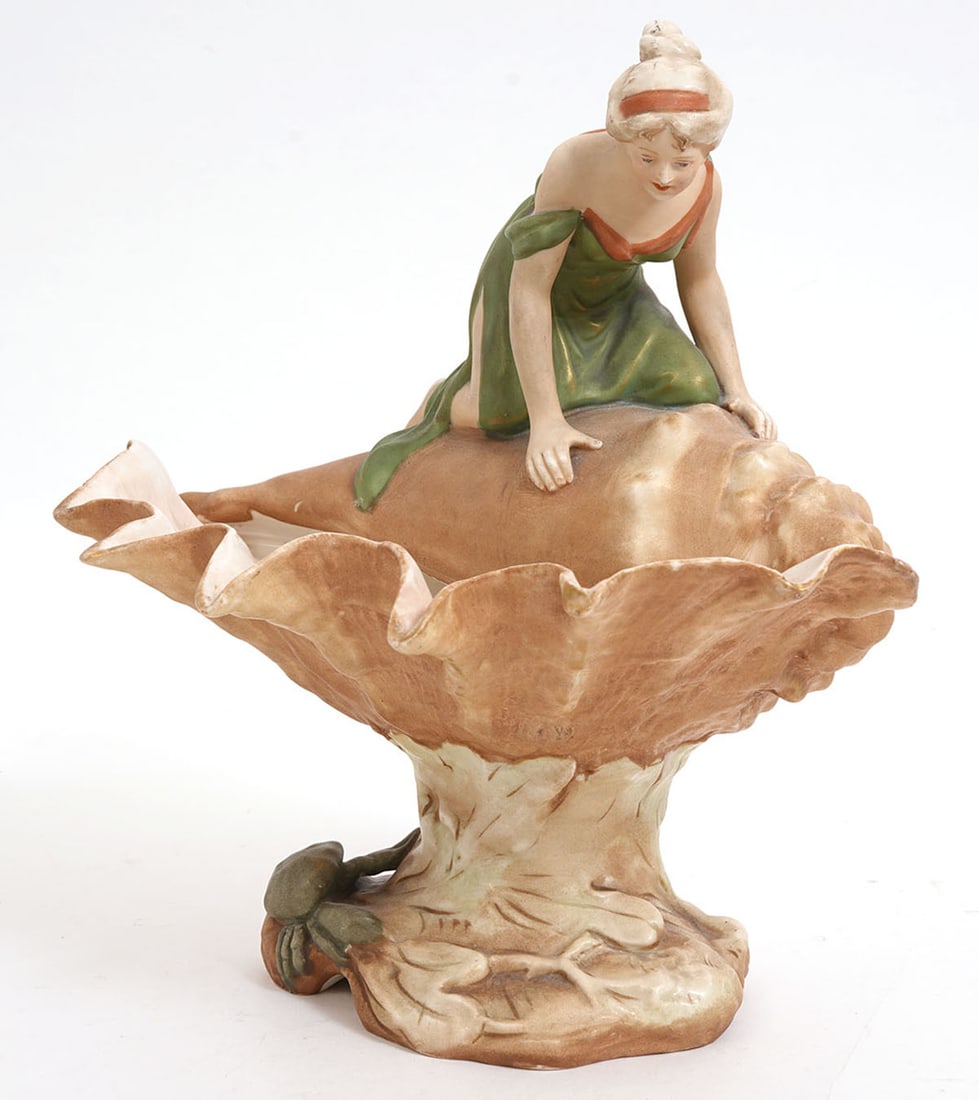 Royal Dux Art Nouveau Porcelain Figurine: Royal Dux Art Nouveau porcelain figurine features woman on a shell and is hallmarked underside. Measures 10.5"L x 7"W x 10.5"H. Condition report: Good condition, please examine all photos closely.