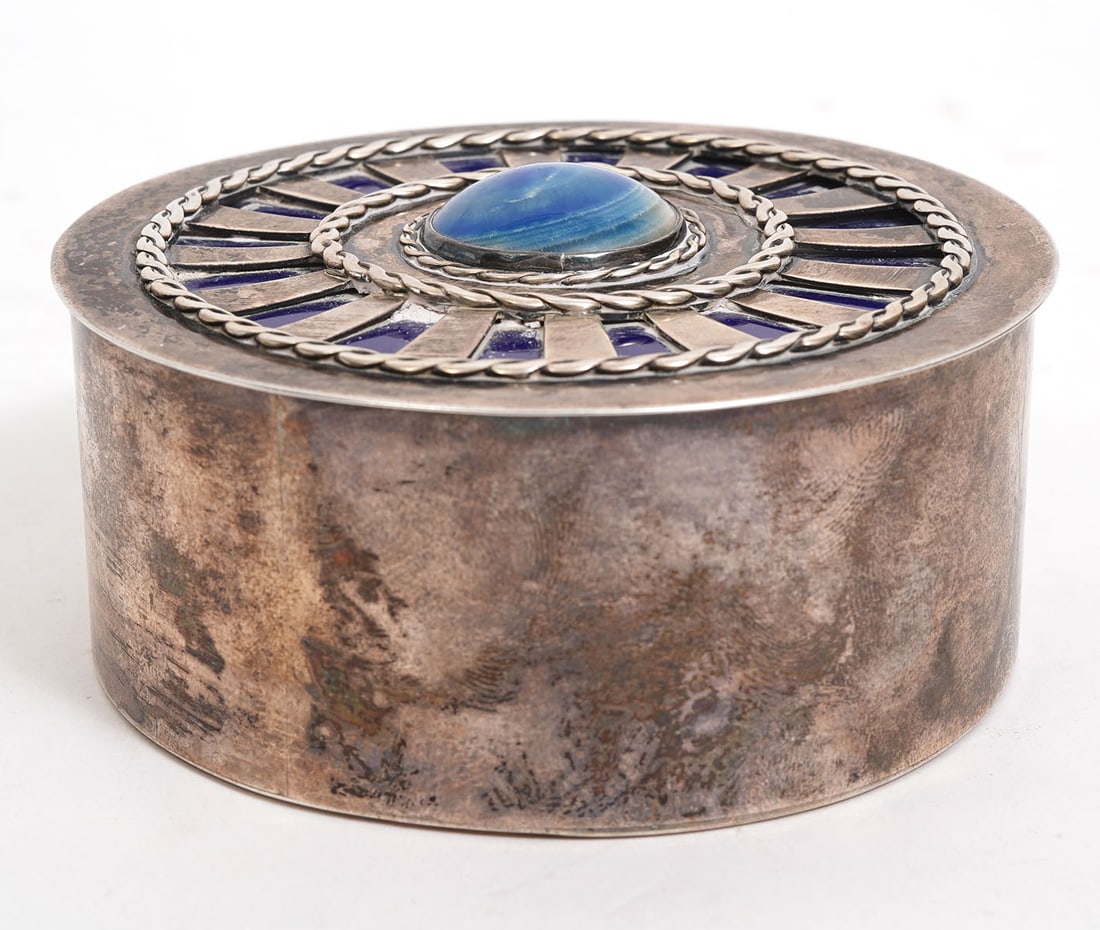 Ruth Erickson Sterling Trinket Box: Ruth Erickson, American (1911-1976). Round decorative sterling trinket box has green stone top center over enamel and is marked on underside. Weighs 239 grams and measures 1.5"H x 3 5/8"W. Condition