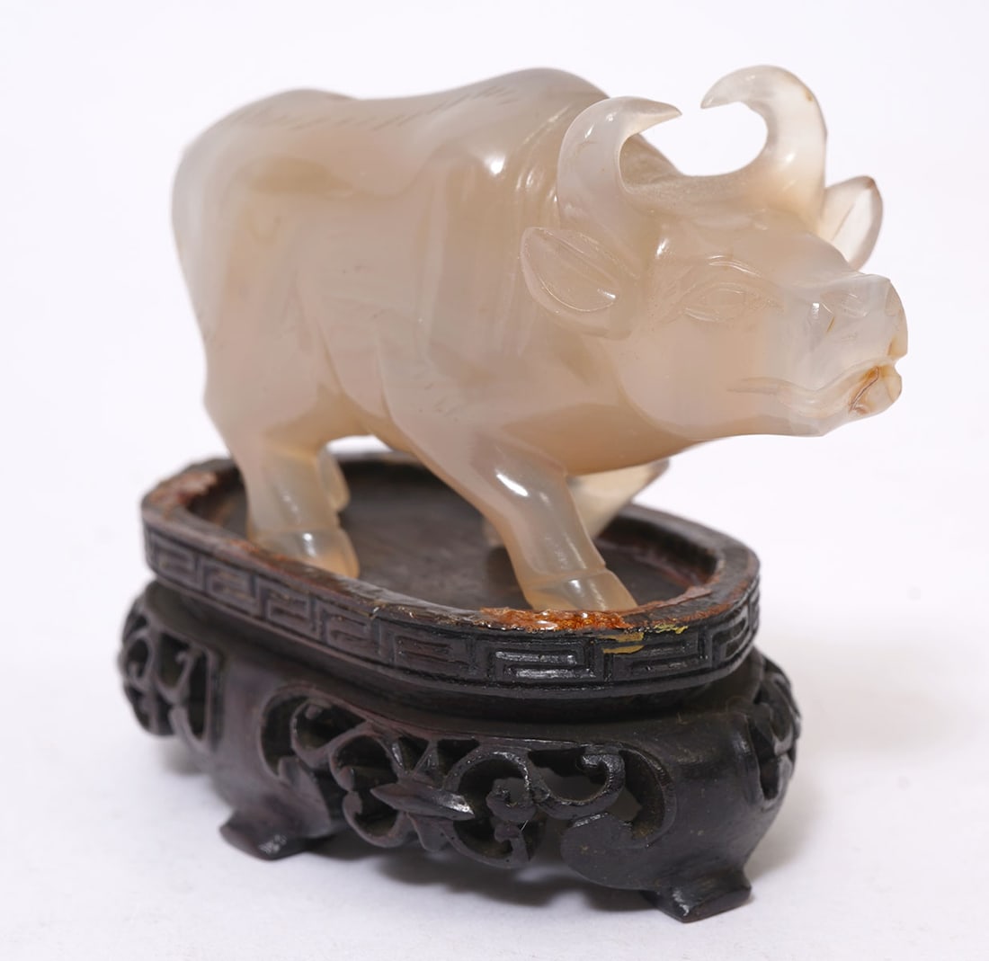 Chinese Carved Green Stone Bull: Chinese carved green stone bull on open work carved wood base. Bull measures 2.25"L x 1.25"H x 1"W; base 2.25"L x 1.25"W x .75"H. Condition report: good condition, please see all photos. Contact C.