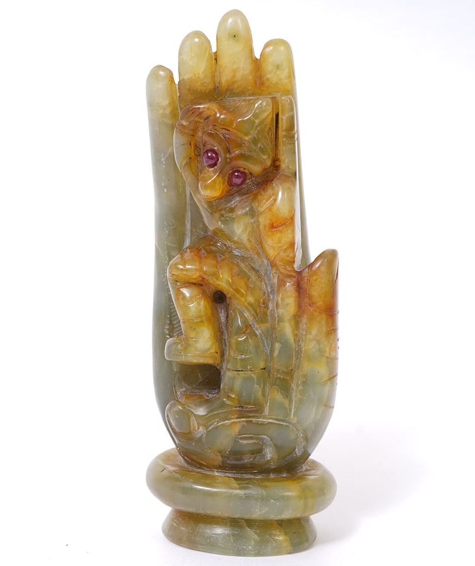 Chinese Carved Hardstone Figural Ornament: Chinese hand-carved hardstone (Possibly jade) ornament of a hand with a figure inside with red stone eyes. Measures (5.5"H x 2"W). Condition report: Good condition, please examine all photos closely. 