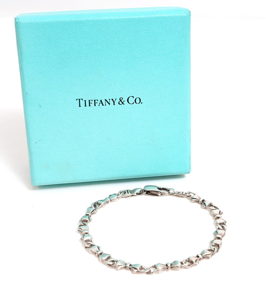 Tiffany & Co. 'Continuous Bows' Stering Bracelet: Tiffany & Co. sterling silver 'Continuous Bows' link bracelet marked 'T & Co 925'. Measures 7.5"L and weighs 15.8 grams. Tiffany box included. Condition report: good condition, no issues please see al