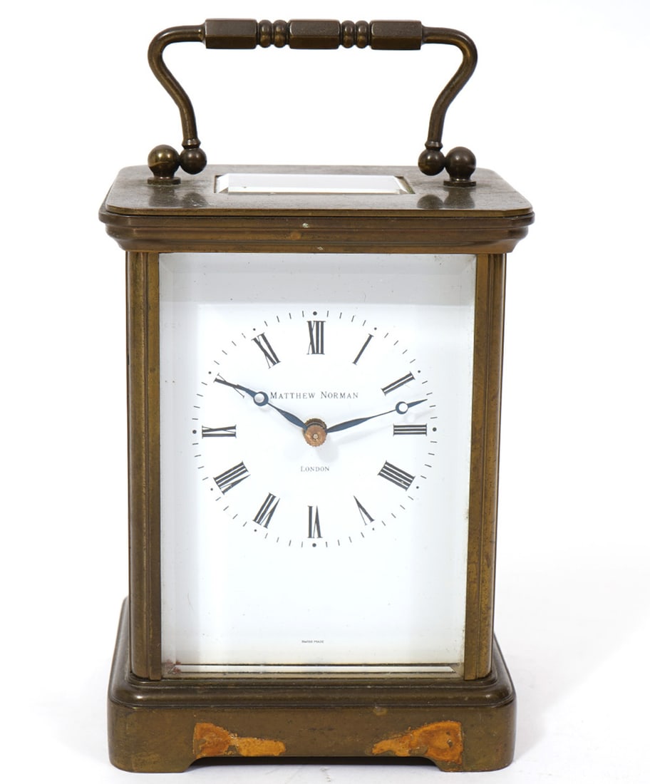 Matthew Norman Brass Carriage Clock: Matthew Norman Brass Carriage Clock with white face, Roman numerals and includes key. Rectangular brass case has a carrying handle and beveled window on top, beveled glass on all four sides. Marked 17